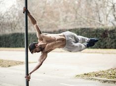 a shirtless man hanging upside down on a pole