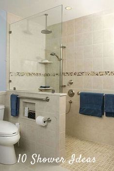 a white toilet sitting next to a walk in shower under a bathroom mirror with blue towels on it