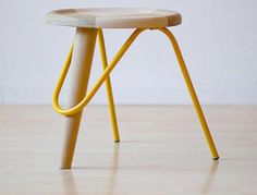 a small wooden stool with yellow legs on a hard wood floor