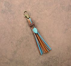 a keychain with a tassel hanging from it's side on a concrete surface