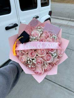 a bouquet of pink roses is held in front of a white van