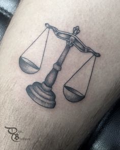 a black and white photo of a tattoo on the leg of a man with an old - fashioned balance scale