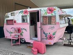 a pink and white trailer with flowers painted on it's side, sitting in a garage