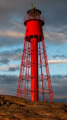 a red light house sitting on top of a hill