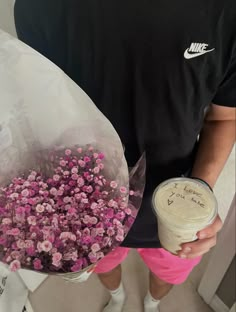 the man is holding a bouquet of flowers and a cup of coffee in his hand