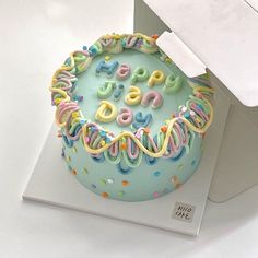 a birthday cake decorated with colorful icing and sprinkles on top of a white box