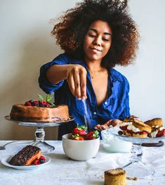 a woman is cutting into a cake with strawberries