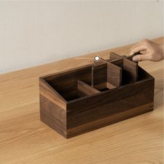 a person is opening the lid of a wooden box on top of a wood table