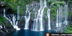 the waterfall is surrounded by lush green trees and blue water in this photo, it looks like they are floating down