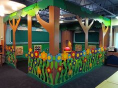 an indoor play area with trees and flowers painted on the walls