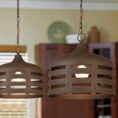 two lights hanging from a ceiling in a room with wood blinds on the windowsill