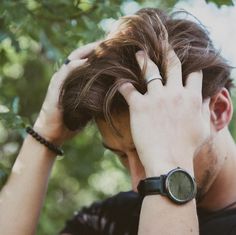 a man with his hand on his head looking at the camera while wearing a watch