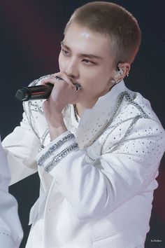 a male in a white shirt and some microphones on his hands with one hand up to his mouth