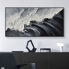 an abstract black and white painting hangs on the wall above a modern dresser in a living room