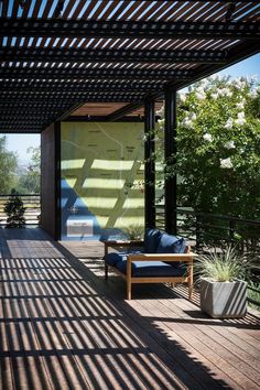 the sun shines through the slatted roof on an outdoor living area with furniture and plants