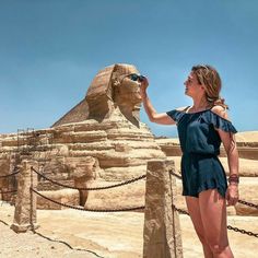 a woman standing in front of the great sphinx at giza, looking up into the sky