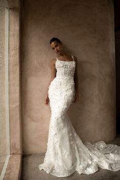 a woman in a white dress standing next to a wall