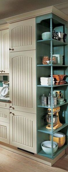 a kitchen with green cabinets and white cupboards in the corner, filled with dishes