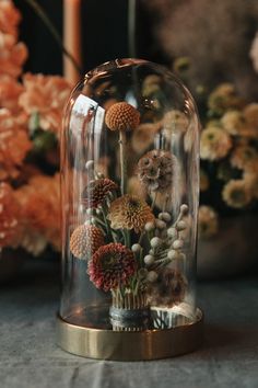 a glass dome with flowers under it on a table