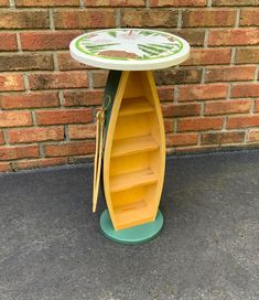 a yellow and green boat shaped table sitting on top of a sidewalk next to a brick wall