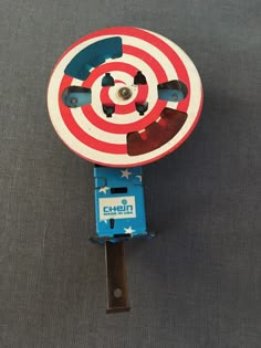 a red, white and blue target toy on top of a gray surface with an arrow in the center