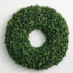 a round boxwood wreath is shown against a white background with the letter o on it