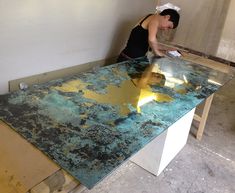 a woman is cleaning the counter top with yellow paint