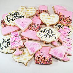 decorated cookies with pink frosting and sprinkles are arranged on a white surface