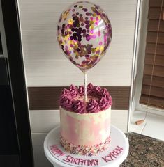 a birthday cake decorated with confetti and a balloon for the first birthday party