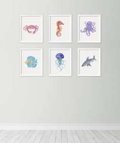 four different sea animals are hanging on the wall in an empty room with white floors