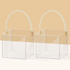 two clear boxes with pearls hanging from the handles on each side, one is empty