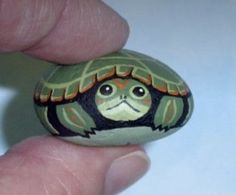 a small turtle painted on top of a rock in the palm of someone's hand