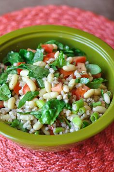 a green bowl filled with salad on top of a red cloth