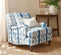 a blue and white chair in a living room with a potted plant on the side table