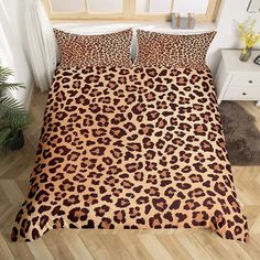 a bed with a leopard print comforter and pillow cases on top of the sheets