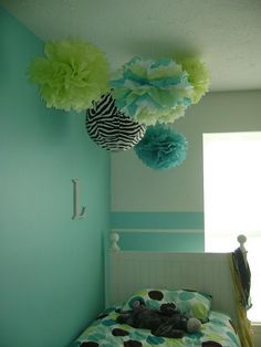 a bed room with a neatly made bed and paper flowers hanging from the headboard