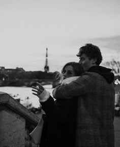 a man and woman standing next to each other in front of a body of water