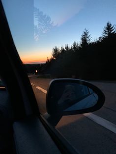 the sun is setting behind some trees on the side of the road as seen from inside a car