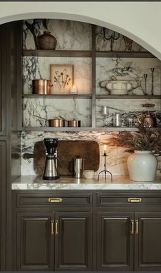 a kitchen with marble counter tops and shelves filled with pots, pans and other items