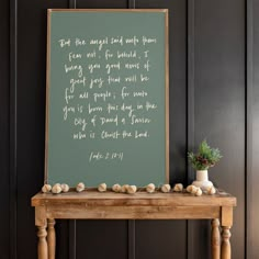 a wooden table topped with a green chalkboard next to a potted plant