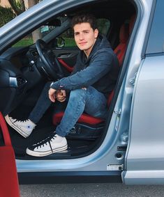 a young man sitting in the driver's seat of a car with his foot on the floor