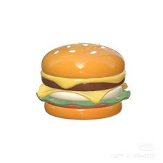 a plastic hamburger with cheese and lettuce on it's bun, sitting in front of a white background