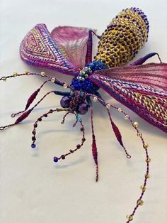 two purple and gold bug sculptures sitting on top of a white table covered in beads