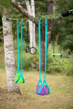 some scissors are hanging from a line in the woods with trees and grass behind them