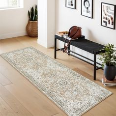 a room with a bench, rug and pictures on the wall