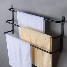 two towels are hanging on the wall next to each other with black metal racks holding white and yellow towels