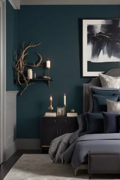 a bedroom with dark blue walls and grey bedding, candles on the nightstands