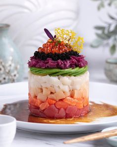 a colorful cake on a white plate with chopsticks