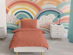 a bed with an orange comforter in front of a colorful wall