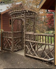 a wooden gate made out of branches in front of a house